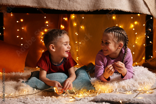 Happy kids in decorated play tent at home