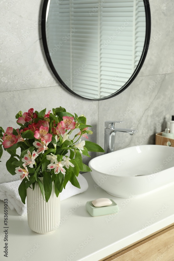 Vase with beautiful Alstroemeria flowers near sink in bathroom Vase with beautiful Alstroemeria flowers near sink in bathroom