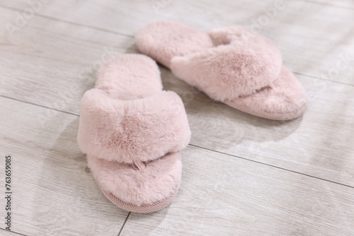 Pink soft slippers on light wooden floor at home, closeup
