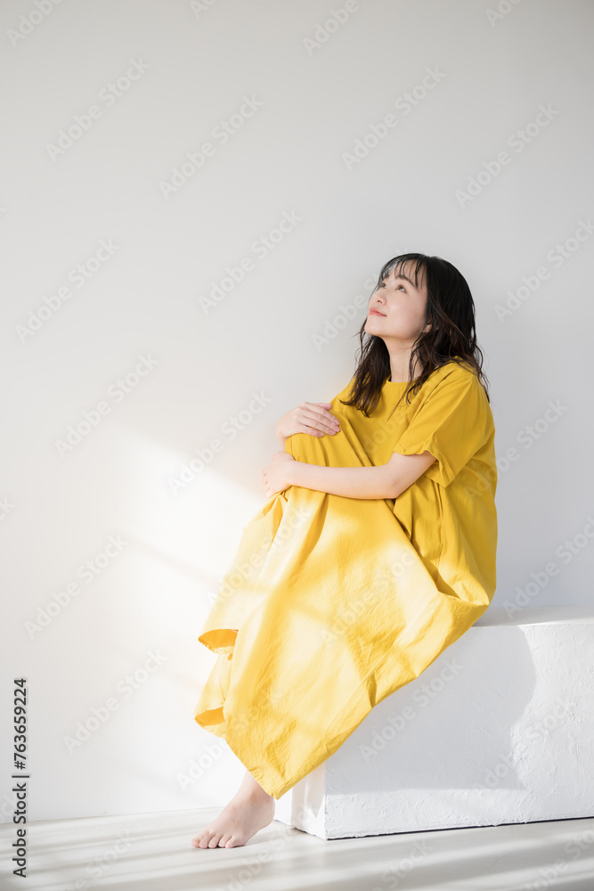 日差しを浴びて黄色のドレスを着た女性　美容やビューティー　太陽のイメージ　日焼けやUVなど