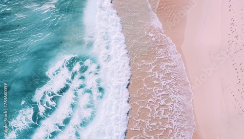 Overhead shot captures the soft foam of waves caressing a sunlit sandy coastline.