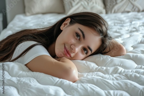 A woman is laying on a bed with her head tilted to the side