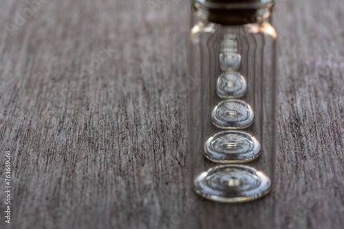 hilera de frascos de vidrio enfocando en la base circular, sobre mesa de madera con espacio para texto,  photo