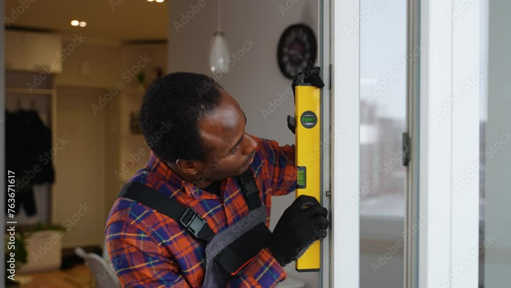 African american windows installation worker in uniform with level tool African american windows installation worker in uniform with level tool