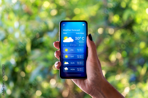 Bilde på lerret Woman outdoors checking the weather forecast on an app on her mobile phone