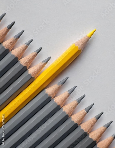 Gray colored pencils, one yellow colored pencil in one line on white paper background with copy space