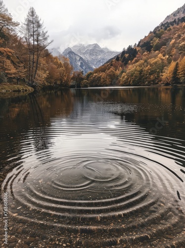 A body of water surrounded by dense trees and towering mountains under a clear sky