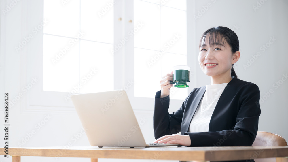 パソコンをしながらコーヒーを飲む女性　休憩やリラックスのイメージ