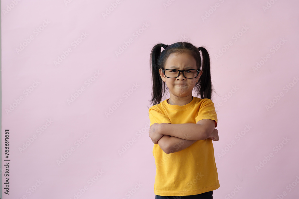 Little girl wearing glasses suffering from headache, hopeless, angry, and stressed because of pain and migraine, hands on head, tired, standing on pink copy space background. Little girl wearing glasses suffering from headache, hopeless, angry, and stressed because of pain and migraine, hands on head, tired, standing on pink copy space background.