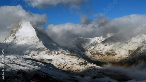 Sun on The Matterhorn peak Zmutt glacier paradise Swiss Pennine Alps valley mountain early morning clouds fog wind October autumn winter Gornergrat railway Zermatt Switzerland landscape slow pan left photo