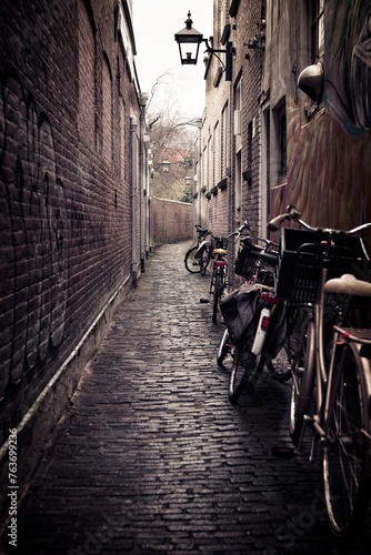 bicycles parked in a narrow laneway leaning against a wall