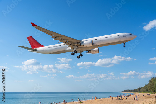 Airplane landing above beautiful beach with people on the beach and sea, travel