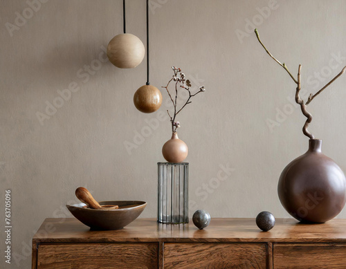 Minimalist composition of living room interior with copy space, wooden sideboard, glass vase with branch, bowl, ball sculpture and personal accessories. Home decor. Template