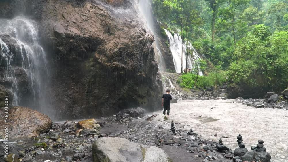 A man admiring a waterfall in a picturesque fluvial landscape A man admiring a waterfall in a picturesque fluvial landscape