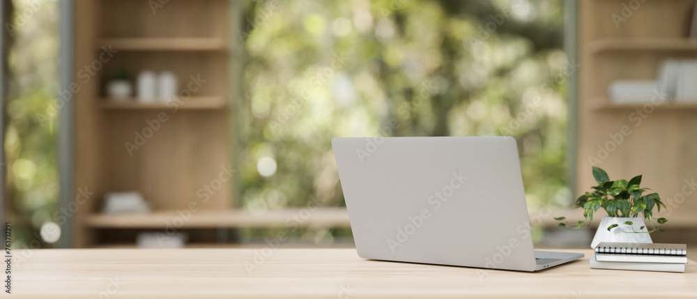Back view image of a laptop computer on a wooden table in a contemporary private office. Back view image of a laptop computer on a wooden table in a contemporary private office.