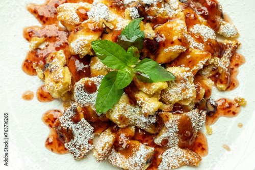 Kaiserschmarrn with iceing sugar and apple sauce on a white plate