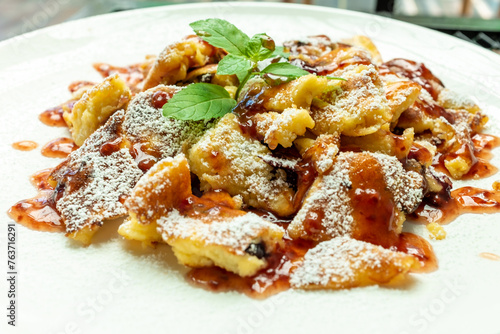 Kaiserschmarrn with iceing sugar and apple sauce on a white plate