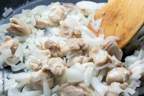 鶏もも肉と玉ねぎをフライパンで炒める調理シーン。
