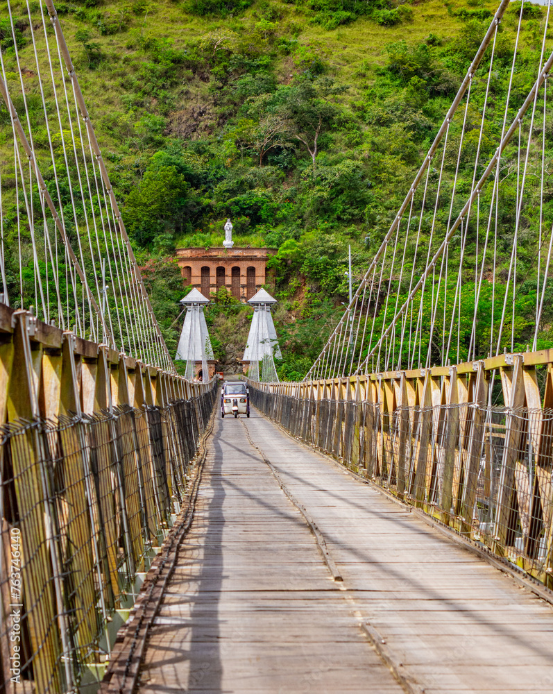 Fototapeta premium Tuk tuk car crossing the iconic Western Bridge, a symbol of Santa Fe de Antioquia