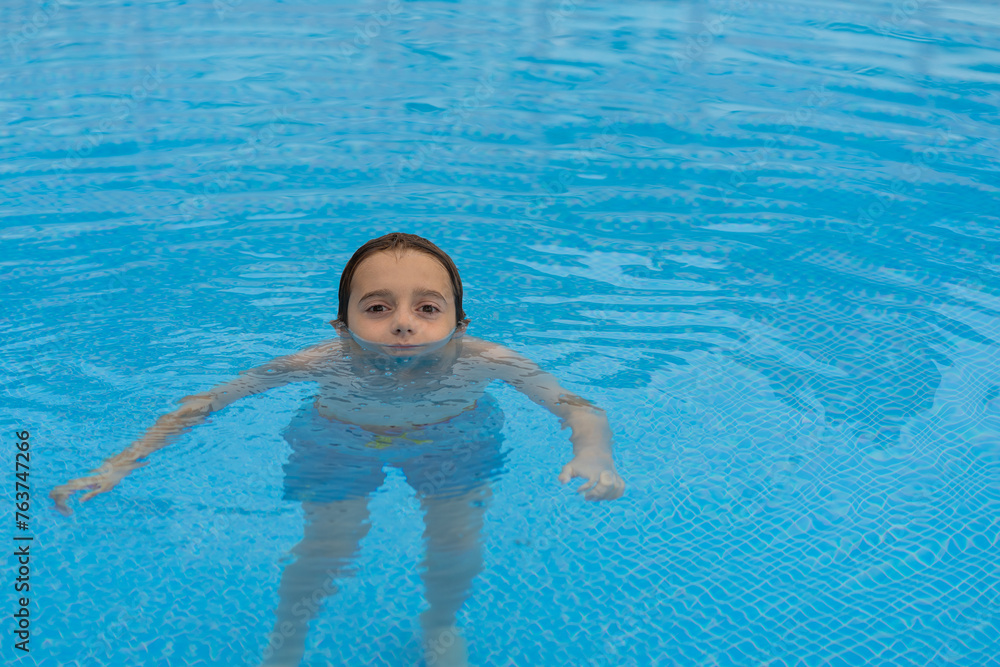 boy submerged in the water of the pool, with only his eyes and nose out of the water