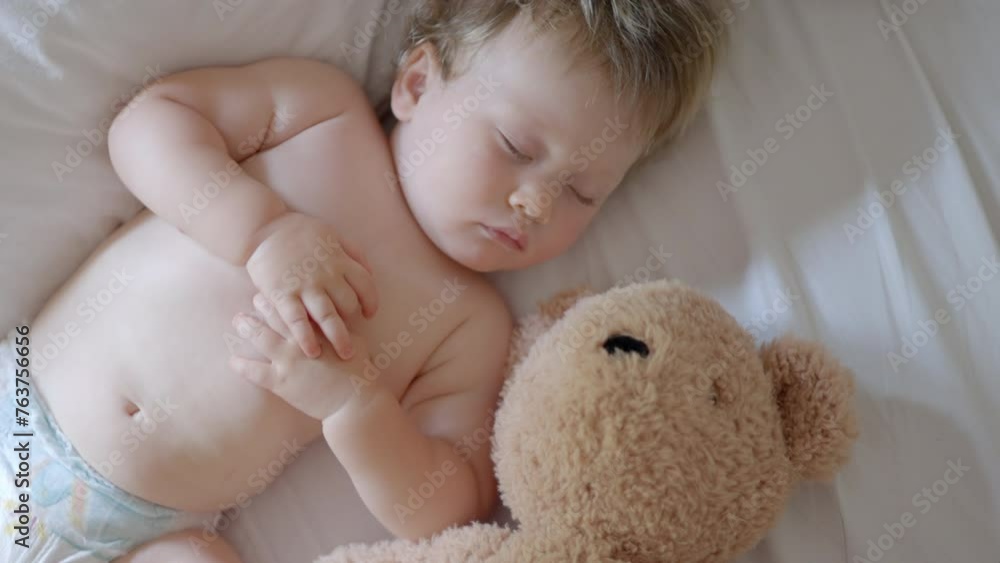 Sleeping baby happy and carefree in bed hugging teddy bear toy. Mother cover with blanket child. Happiness sleep, children without coughing. cute little boy sleeps sweetly in crib sees colorful dream Sleeping baby happy and carefree in bed hugging teddy bear toy. Mother cover with blanket child. Happiness sleep, children without coughing. cute little boy sleeps sweetly in crib sees colorful dream