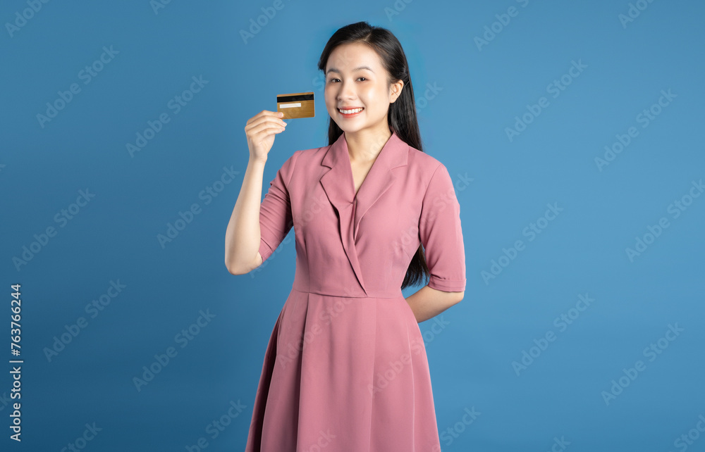 Image of Asian businesswoman posing and holding credit card on a blue background Image of Asian businesswoman posing and holding credit card on a blue background