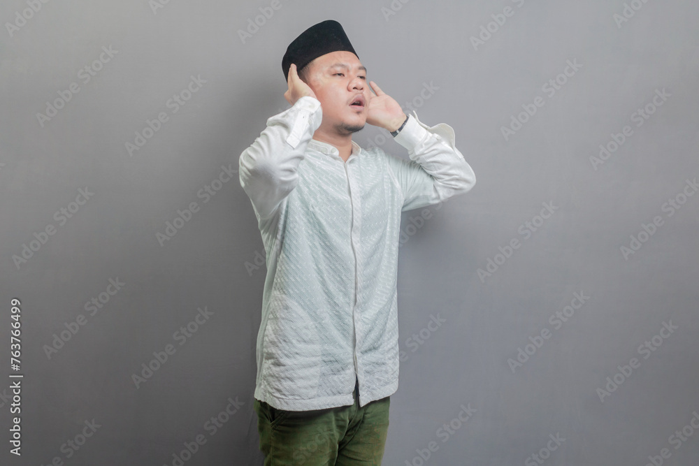 Asian Muslim man standing reciting the call to prayer Asian Muslim man standing reciting the call to prayer