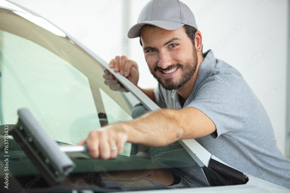 experienced mechanic is cleaning the front window of a car experienced mechanic is cleaning the front window of a car