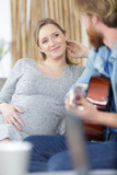 man playing guitar to his pregnant partner