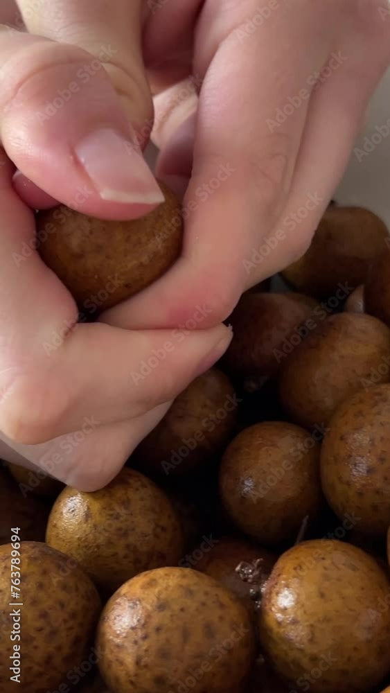 Person peeling longan fruit. a sweet. tropical delicacy in Southeast Asia. by hand over a white. ceramic plate. 4k footage Person peeling longan fruit. a sweet. tropical delicacy in Southeast Asia. by hand over a white. ceramic plate. 4k footage