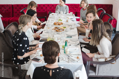 Women sitting at long table on meeting and communicating. French breakfast, French lesson for adults.