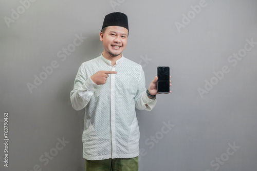 Portrait of an Asian Muslim man smiling pointing finger to his smartphone