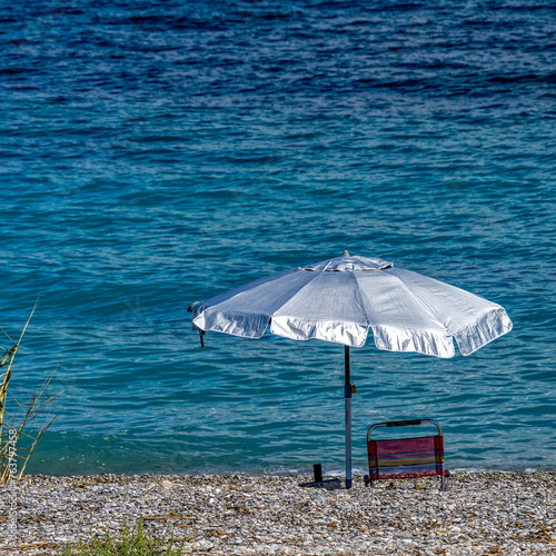 A lonely umbrella on a tranquil beach with blue sea and under a spectacular sky. Summer is coming.