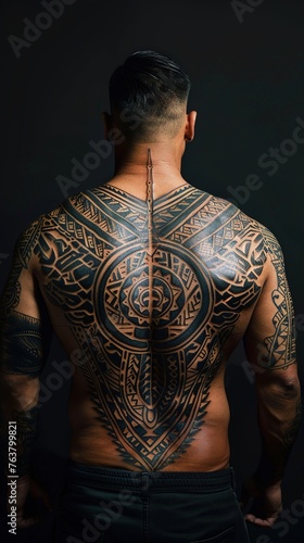 The bold presence of a tribal-inspired sleeve tattoo on a man's upper back, its intricate patterns and dynamic lines standing out against a clean, solid backdrop.