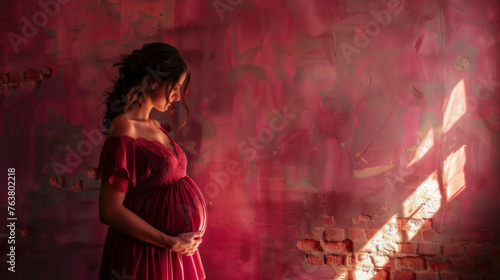 Young pregnant woman against the red background. Waiting for the birth of a child