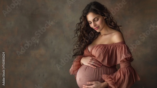 Young pregnant woman against the dark studio background. Waiting for the birth of a child