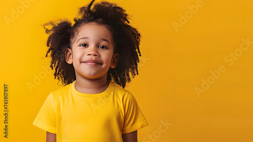 cheerful mockup exhibiting a happy young black curly hair boy in a yellow t-shirt against a bright yellow background, radiating positivity and joy