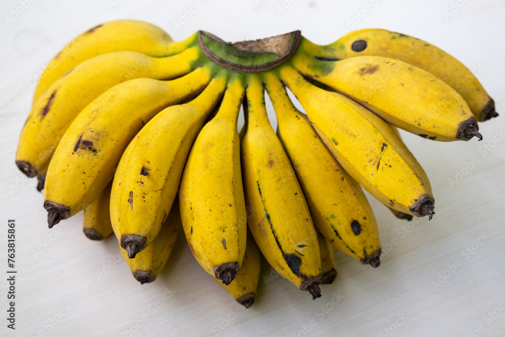 A bunch of fresh ripe yellow bananas on a wooden background. Bananas are healthy fruit. It contains potassium, magnesium, vitamin B6, fiber, tryptophan, and antioxidants. - obrazy, fototapety, plakaty 
