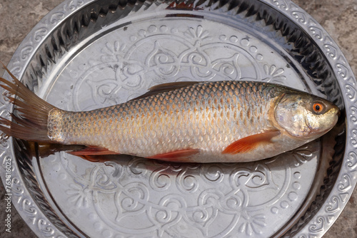 Whole Rui Fish on a dish. This fish is also called Rohu fish, Indian carp, Ruhi, or Roho labeo (Labeo rohita). It is a species of fish of the carp family, found in rivers in South Asia. photo