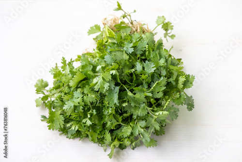 Fresh coriander leaves on a white wooden background. Locally in Bangladesh, It is called Dhone Pata and is also known as cilantro, Chinese parsley, Mexican parsley, and Dhania.  photo