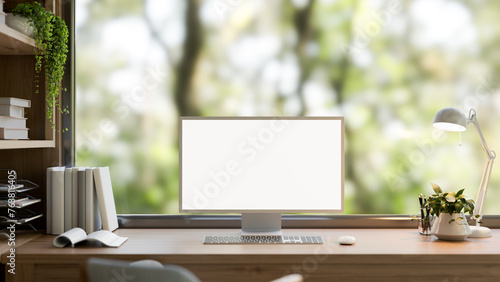 A computer mockup on a wooden desk in a contemporary home office with neutral wood accents. © bongkarn