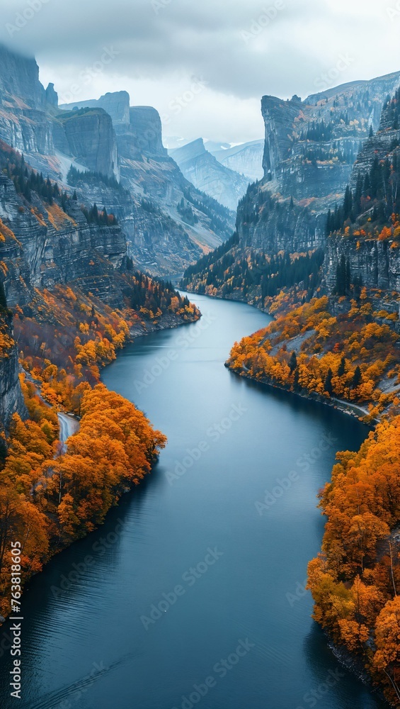 An aerial perspective of a winding river cutting through a deep mountain gorge, with autumn colors painting the scene