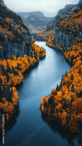 An aerial perspective of a winding river cutting through a deep mountain gorge, with autumn colors painting the scene photo