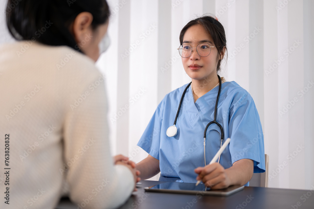 A professional Asian female doctor is working in her office, talking and giving advice to a patient. A professional Asian female doctor is working in her office, talking and giving advice to a patient.