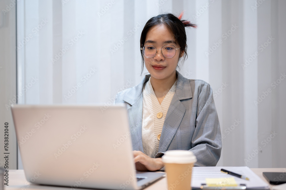 A confident Asian businesswoman is working on her laptop computer in her office. A confident Asian businesswoman is working on her laptop computer in her office.
