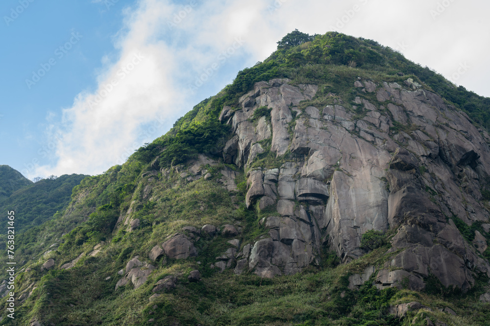 Naklejka premium Look up to the mountain, gorgeous rocks make a great cliff, grass growing between the rocks, in Jinguashi, New Taipei City, Taiwan.
