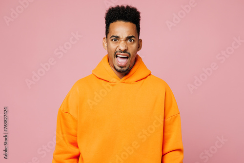 Young sad mad angry man of African American ethnicity wear yellow hoody casual clothes look camera scream shout cry isolated on plain pastel light pink background studio portrait. Lifestyle concept.