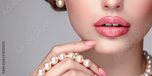 Beautiful woman with pink manicure, beautiful lips and pearl necklace on white background