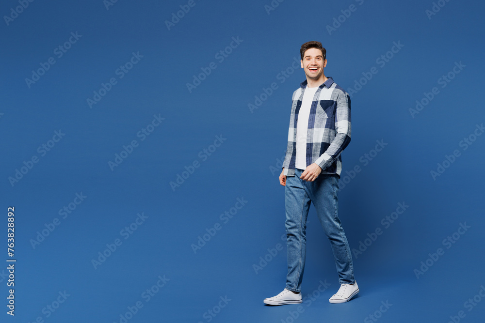 Full body side view young smiling satisfied happy man he wears shirt white t-shirt casual clothes walk go look camera isolated on plain blue cyan color background studio portrait. Lifestyle concept. Full body side view young smiling satisfied happy man he wears shirt white t-shirt casual clothes walk go look camera isolated on plain blue cyan color background studio portrait. Lifestyle concept.