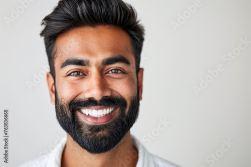 Portrait of smiling man with beard against neutral background. Positive human emotions.